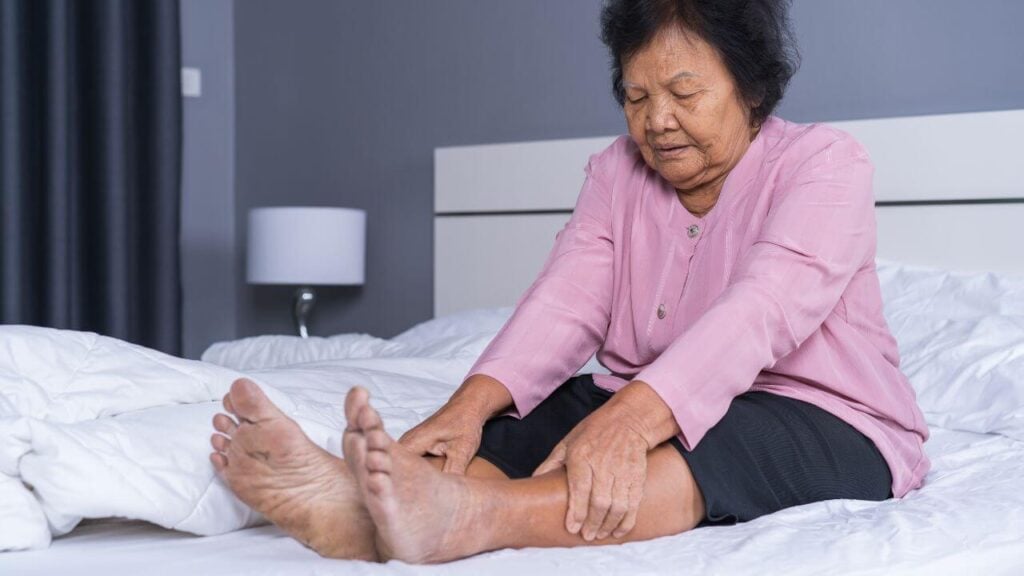 An old woman on the bed felt pain in her legs
